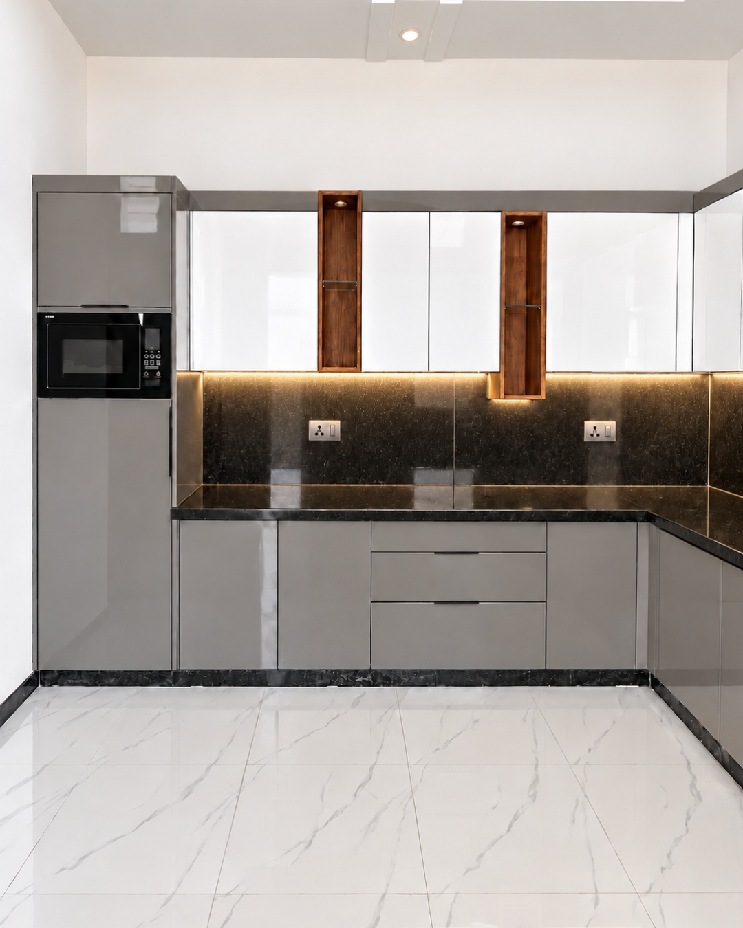 2 Pearl white and grey kitchen with glossy cabinets, illuminated wood look display niches, black countertops and a microwave in a tall cabinet.