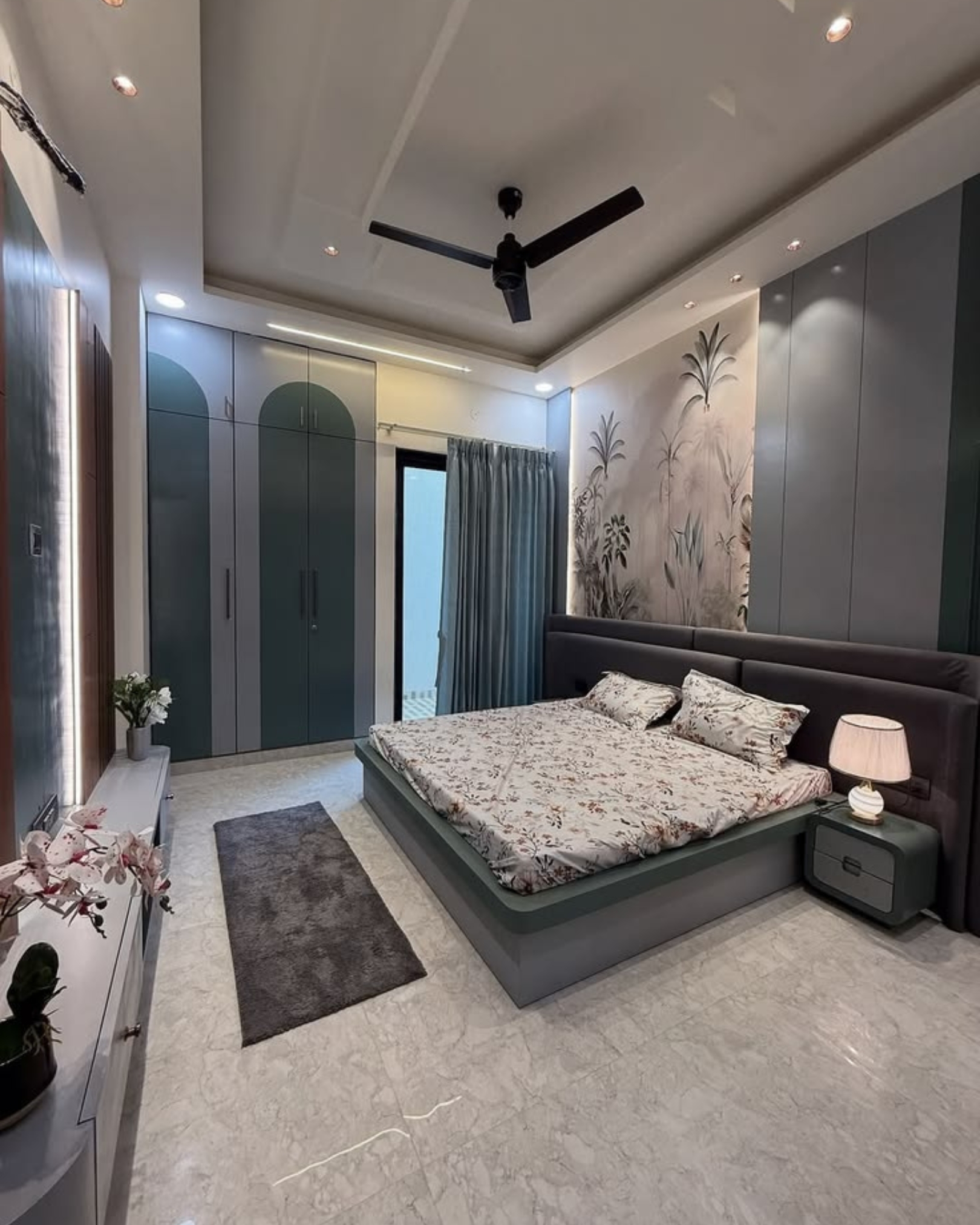 Grey and muted green bedroom with arched wardrobe detailing, an upholstered headboard and a botanical feature wall.