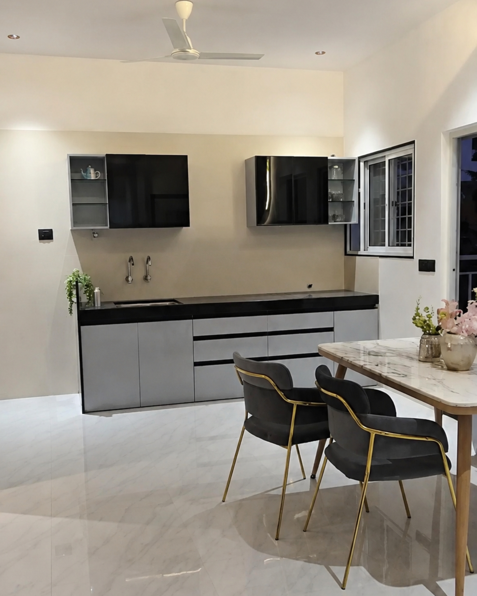 Straight kitchen with grey base cabinets, glossy black wall cupboards and a black countertop beside the dining area.