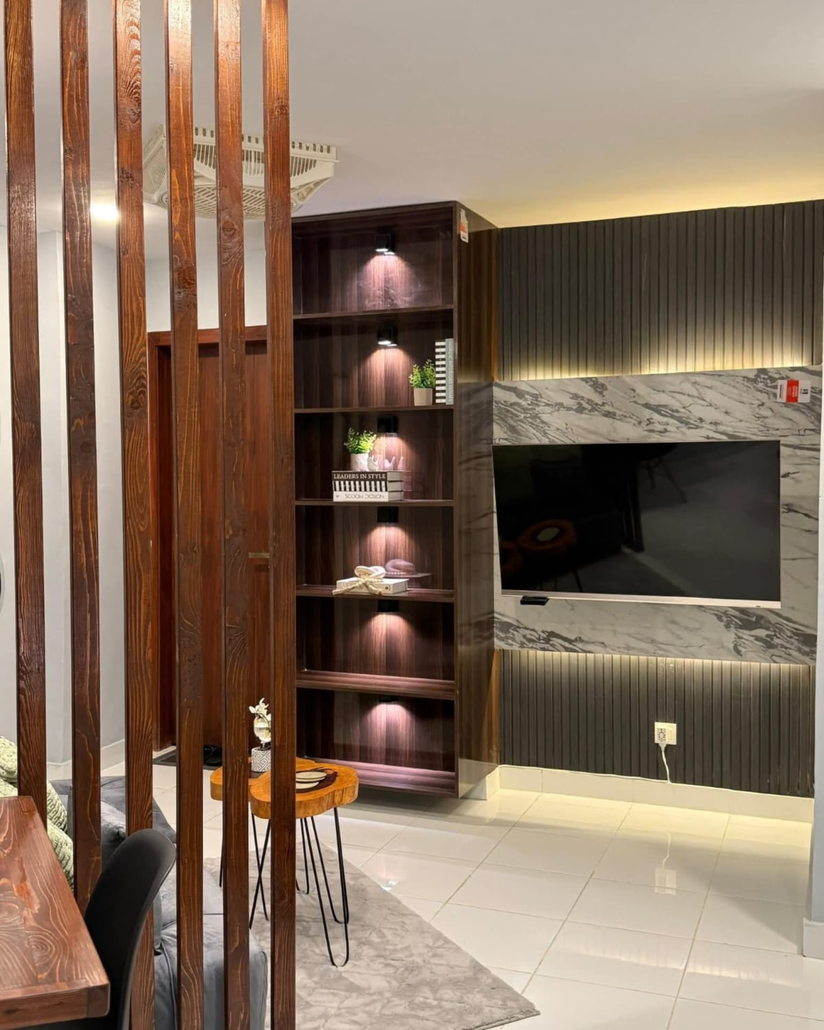 5 Marble effect TV feature wall with charcoal fluted panels, warm backlighting and tall illuminated wood-look display shelves.