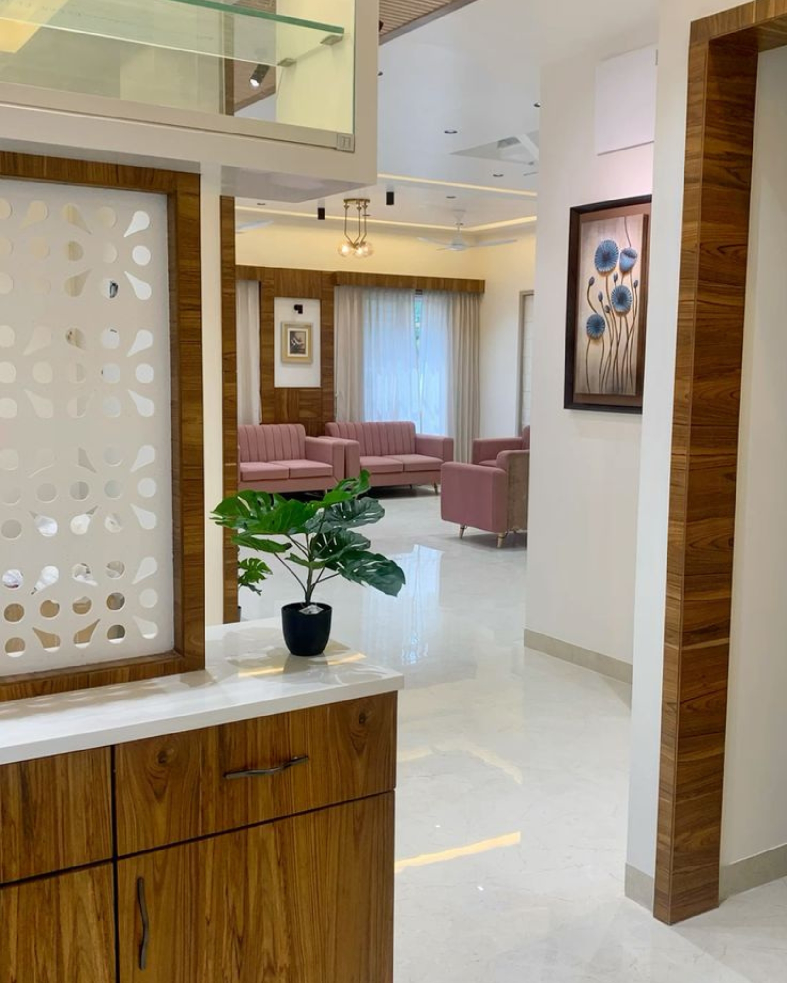 5 Decorative white cutout partition above a wood-look cabinet, opening towards a living room with soft pink seating.
