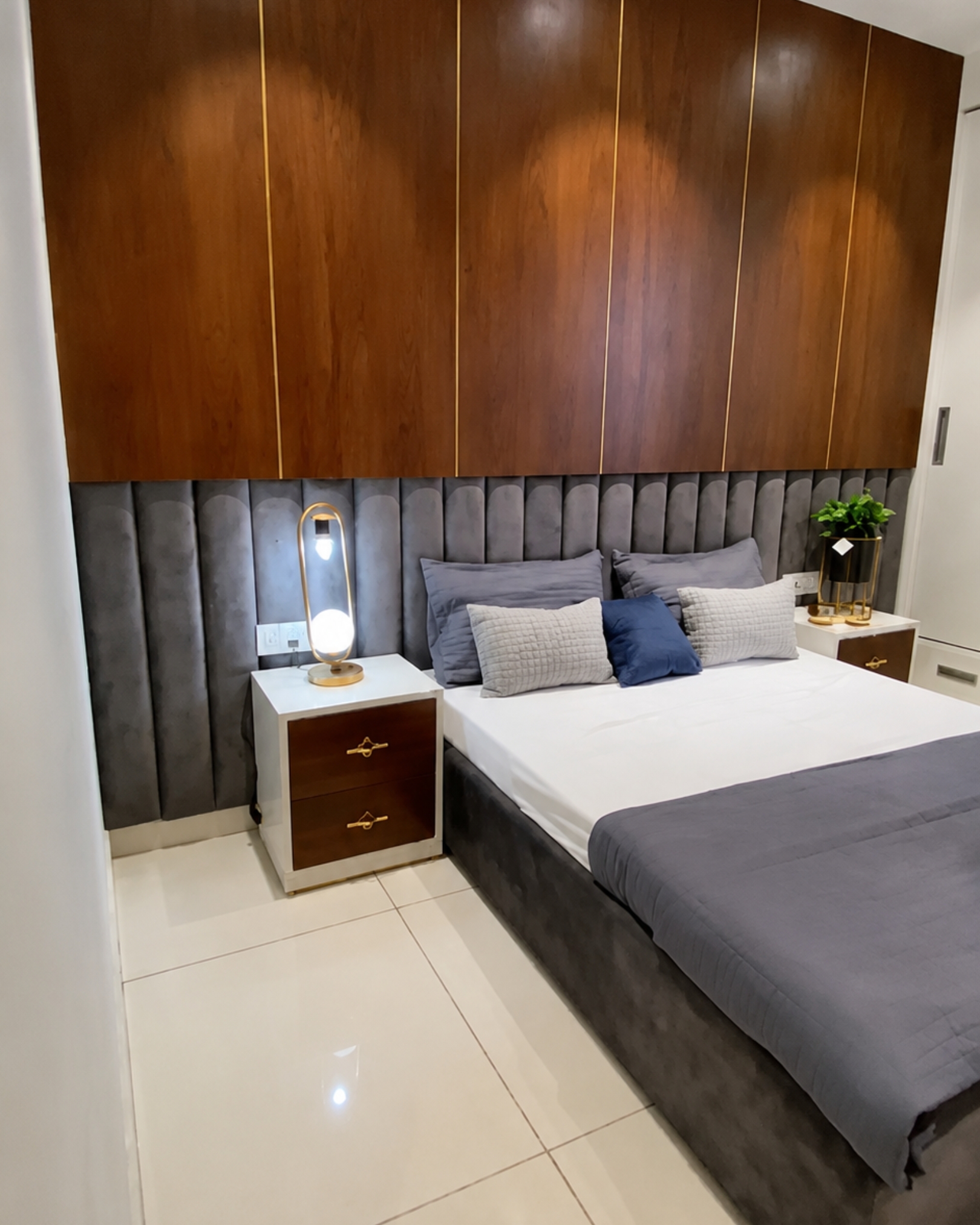 6 Grey channeled headboard beneath wood look panels with gold trim, paired with white and wood look bedside drawers.