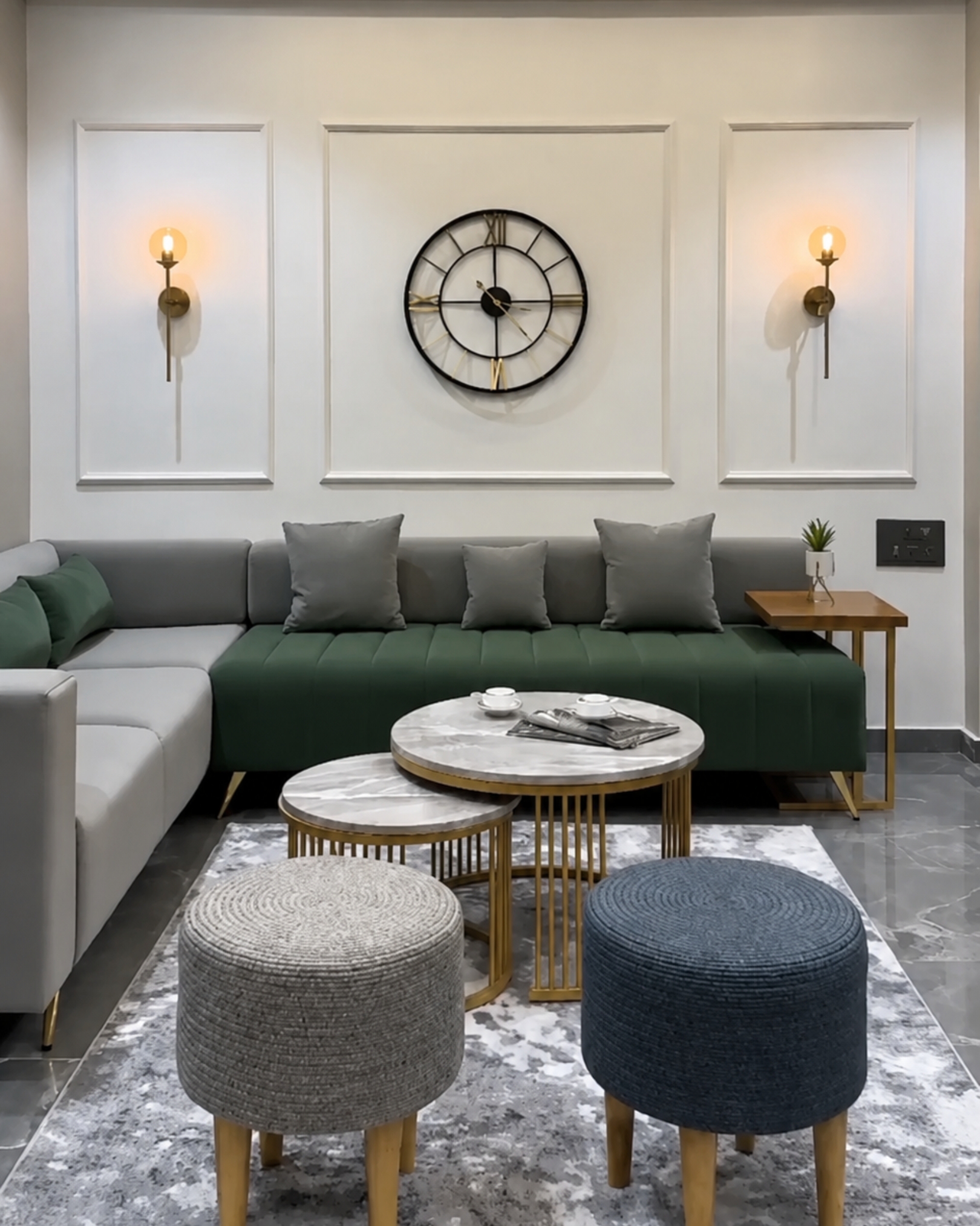 Green and grey sectional sofa beneath decorative wall mouldings, with nesting coffee tables and round upholstered stools.