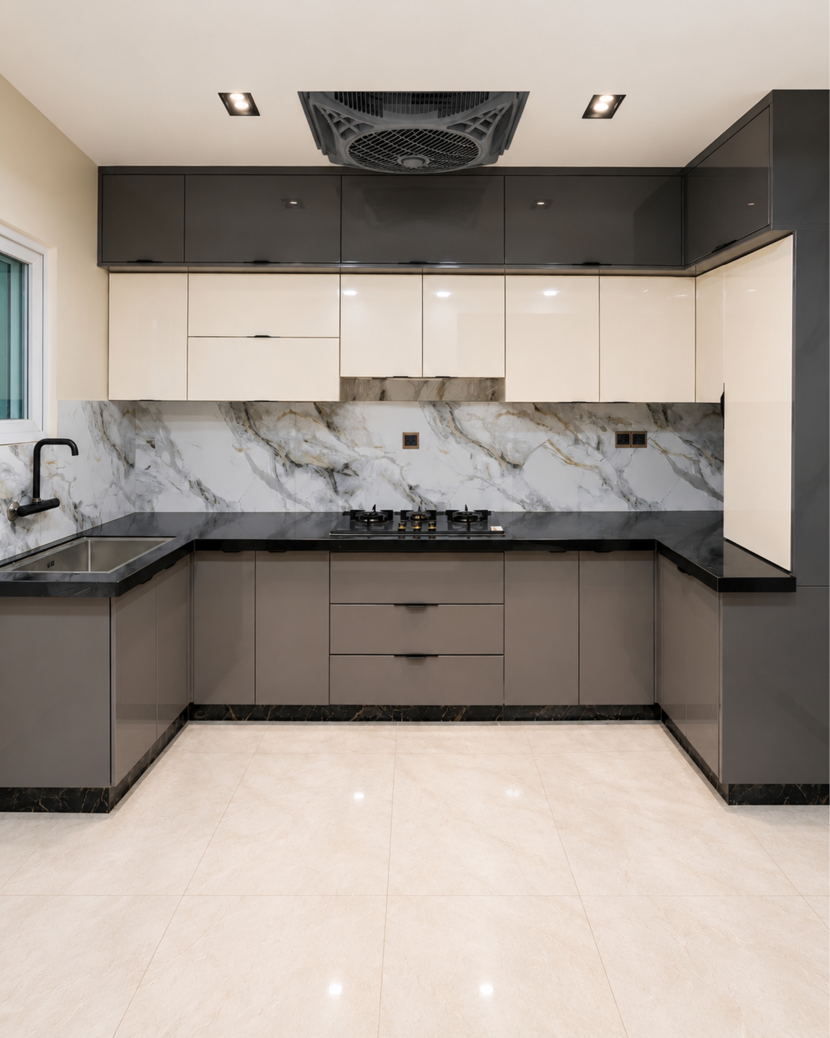 Modern U shaped kitchen with charcoal and ivory upper cabinets, taupe base cabinets, black countertops, a marble effect backsplash and cream tiled flooring.