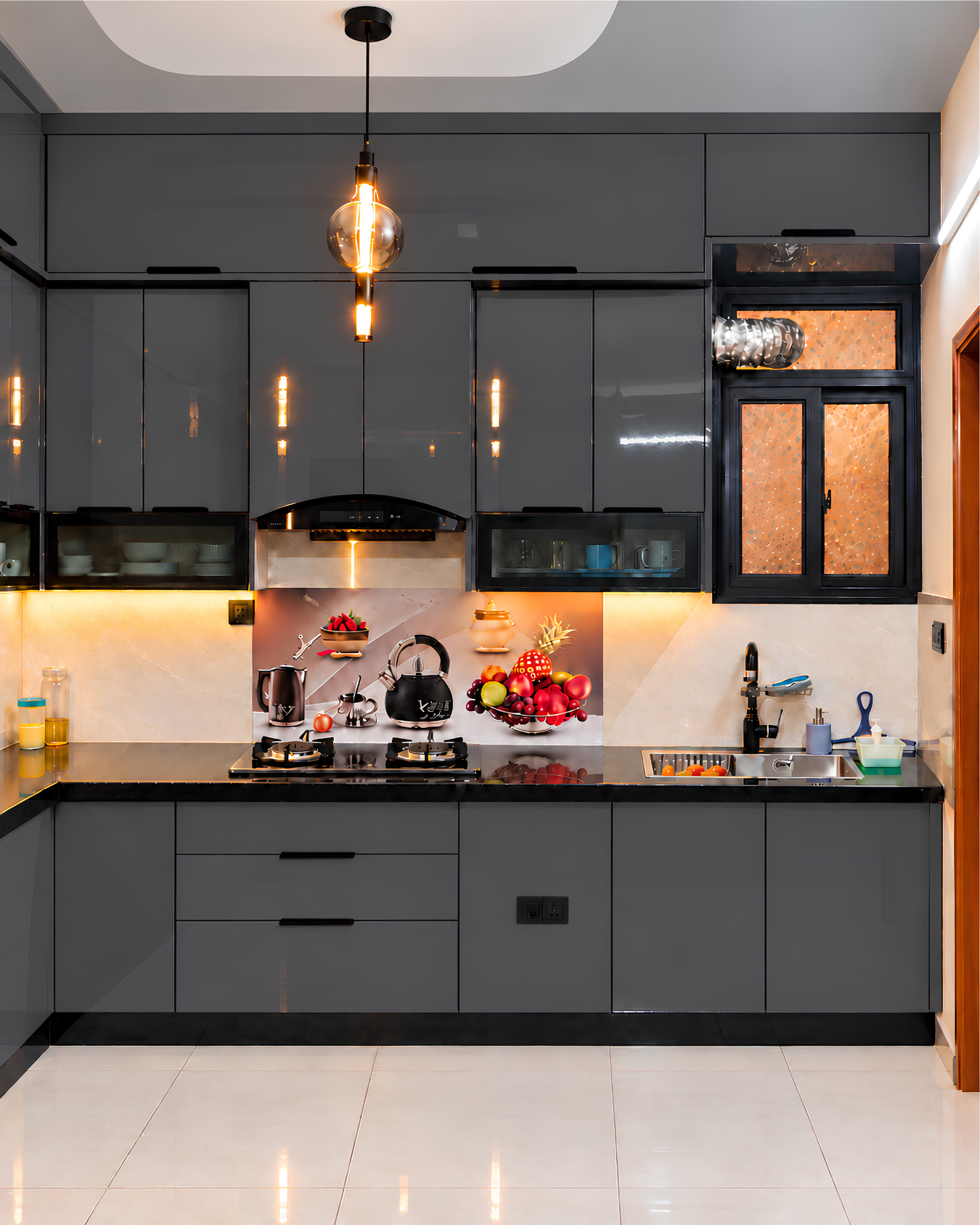 Front view of graphite kitchen cabinetry with a curved cooker hood, gas hob, fruit and teapot backsplash and sink beneath a window.